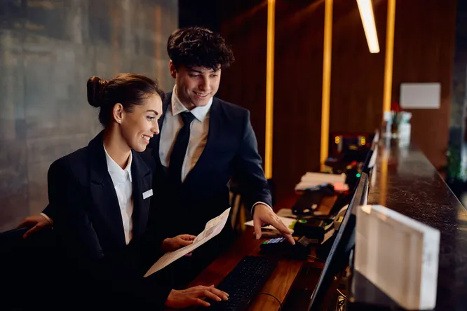 Zwei Hotelangestellte arbeiten an der Rezeption